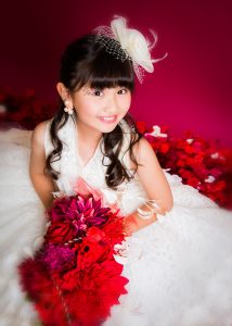 Yune wearing a white dress holding red flowers